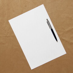 Template of white paper with pen lies diagonally on light brown cloth background. Concept of business plan and strategy. Stock photo with empty space for text and design.