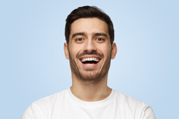 Attractive handsome unshaven young man in white t-shirt laughs out loud