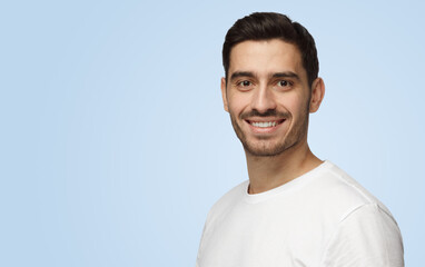 Attractive young handsome European man in white T-shirt stands on right side smiling © Damir Khabirov