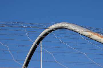 Metal arc of a greenhouse with wire mesh against blue sky