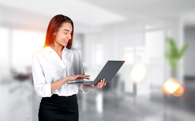 Young office woman typing on computer, office room blurred