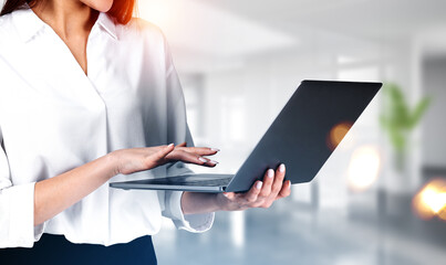 Businesswoman wearing formal wear is holding laptop standing at