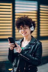 Woman walking in the city streets and using smartphone and headphones