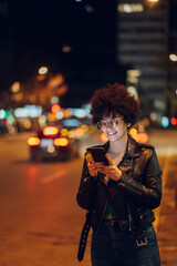 Woman with afro hair using a smartphone outside in the city