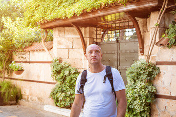 Bald Caucasian man walks streets in Turkey in Antalya, enjoys views in light colored T-shirt with...