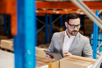 A supervisor using tablet to check on goods in warehouse.