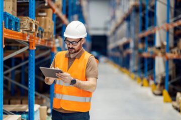 A warehouse supervisor scrolling on tablet.