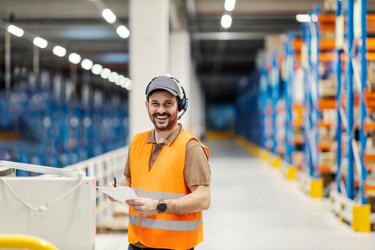 A supervisor with voice picking headset going trough check list and smiling at the camera in delivery center.