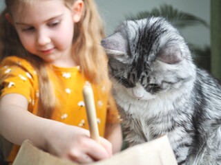 Little toddler girl planting seeds in the pots with cat. Love of pets. Funny and curious pets. Home gardening, transplanting plants, seedlings