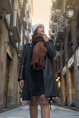 three quarter length shot of a latin young lady standing on an alley of the downtown of the city looking up