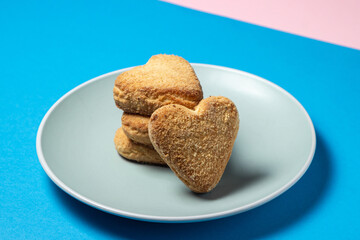 Shortbread cookies in a plate on a colored background. Heart shaped cookies.