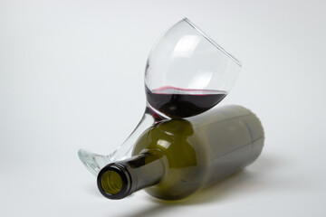 A glass of red wine with an empty bottle on a white background. Excessive alcohol consumption.