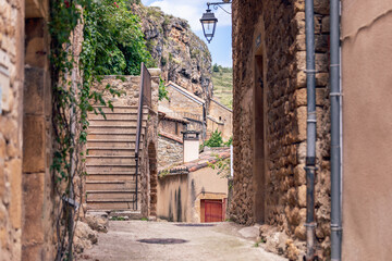 Fototapeta na wymiar Small tangled streets with medieval buildings, stairs, drain and water pipes, street lighting of ancient Peyre village. Aveyron, Occitania, France