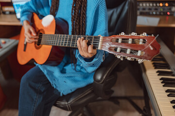 Plakat Focus on the hands of a guitarist keeping fingers on the strings while playing the guitar in the sound recording studio