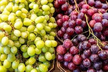 Market stall with green and blue grapes.