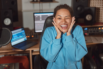 Funny cheerful African woman, sound engineer or radio presenter grimacing looking at camera in the...