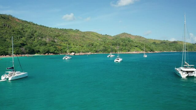 Aerial dolly above the emerald water of bay between white catamarans