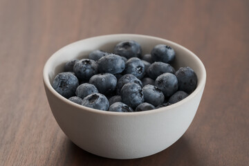 Fresh washed blueberries in white bowl on walnut table