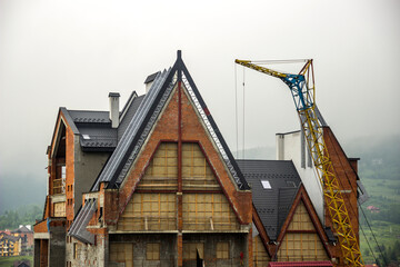 construction site with crane and unfinished cottage in Ukrainian Carpathian village