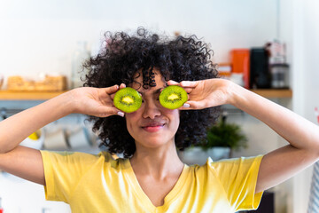 Beautiful latino woman with curly hair at home preparing an healthy vegan meal with fruit in the kitchen