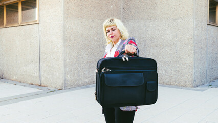 La pesada y explotada carga laboral en los trabajos en la actualidad, renunciando al trabajo de oficina, mujer moderna levantando un maletín negro   - obrazy, fototapety, plakaty