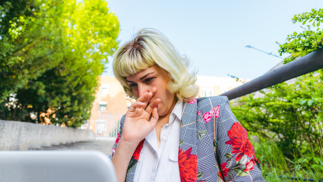 El cansancio por las largas horas de trabajo, mujer bostezando mientras trabaja, chica joven teletrabajando al aire libre 