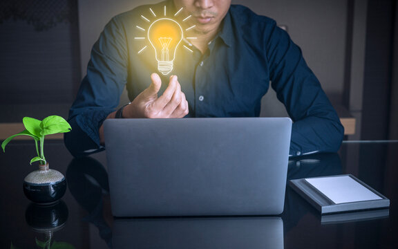 Business man holding a light bulb ,thinking for new idea and working on desk with laptop 
