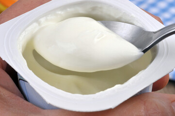 Manger un yaourt nature avec une cuillère en gros plan