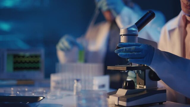 Scientists are analyzing samples in medical research laboratory. Scientific searching for vaccine with microscope to treat diseases in medicine. Pharmaceutical Lab and biotechnology development