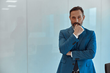 Relaxed middle-aged man standing with folded arms against white background, looking at the camera, copy space