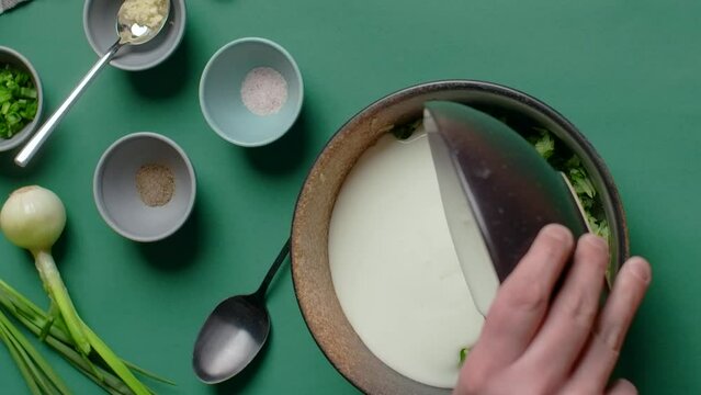 Vertcial flat lay cooking food: making cold soup with kefir and grated cucumber