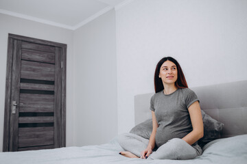 Young preganant woman expecting a baby relaxing on bed indoors