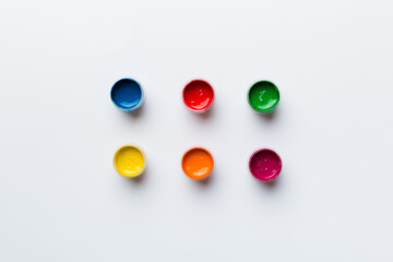 jars with gouache of different colors on Colored background. hobby painting. Top view with empty space. workplace for creativity. home teaching concept drawing