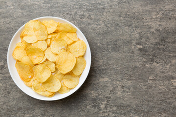 Potato chips on bowl isolated on colored background. Delicious crispy potato chips in bowl. Space for text. Top view