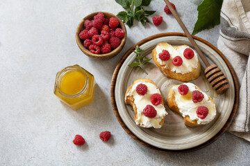 Healthy summer breakfast with sweet sandwiches with ricotta, raspberries and honey on a stone table. Copy space.
