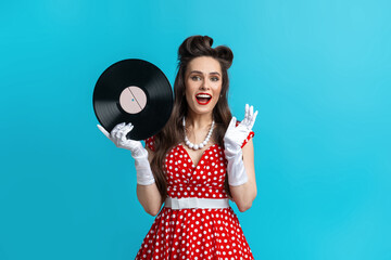 Retro music, old songs, nostalgia. Excited young pinup woman in retro polka dot dress holding...