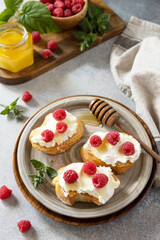 Healthy summer breakfast with sweet sandwiches with ricotta, raspberries and honey on a stone table.
