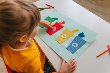 Little girl playing with poster of garbage containers for sorting at kindergarten