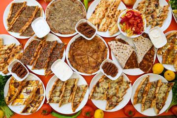  Traditional Turkish cuisine. Pizza, pita, pidesi, sucuk, hummus, kebab. Many dishes on the table. Serving dishes in restaurant. Background image. Top view, flat lay