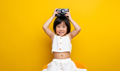 Asian female photographer taking a picture on a yellow background Has a cute smile like a childhood