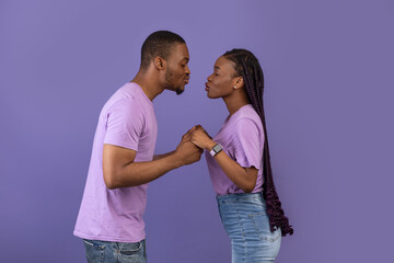 Naklejka premium African American man kissing his woman at studio