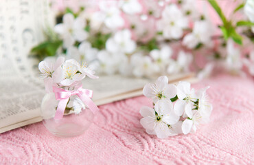 old newspaper and a vase with white small flowers on a pink background