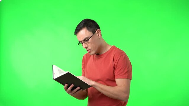 Clever man in eyeglasses and red t shirt reading book
