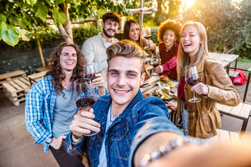 Group of friends having barbeque dinner party - Young people taking selfie drinking red wine together - Friendship concept with guys and girls dining outside - Bright filter