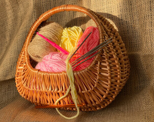 The threads are yellow and pink in a brown basket. Knitting and crochet. Shopping cart with items on a brown background.