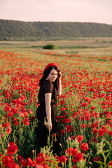 Obraz na płótnie Canvas woman in black dress on sunset at the poppies flowers field