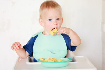 kid eats with a spoon and learns by himself