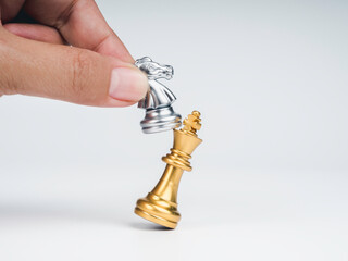 Close-up horse, silver knight chess piece attack the gold king isolated on white background. Hand...