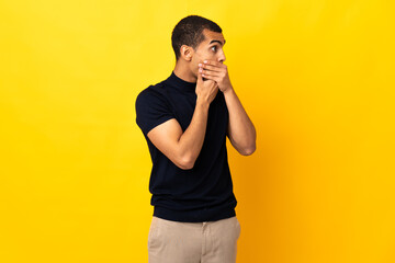 African American man over isolated background covering mouth and looking to the side