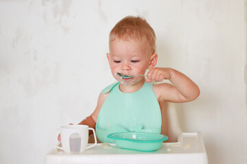 kid eats with a spoon and learns by himself